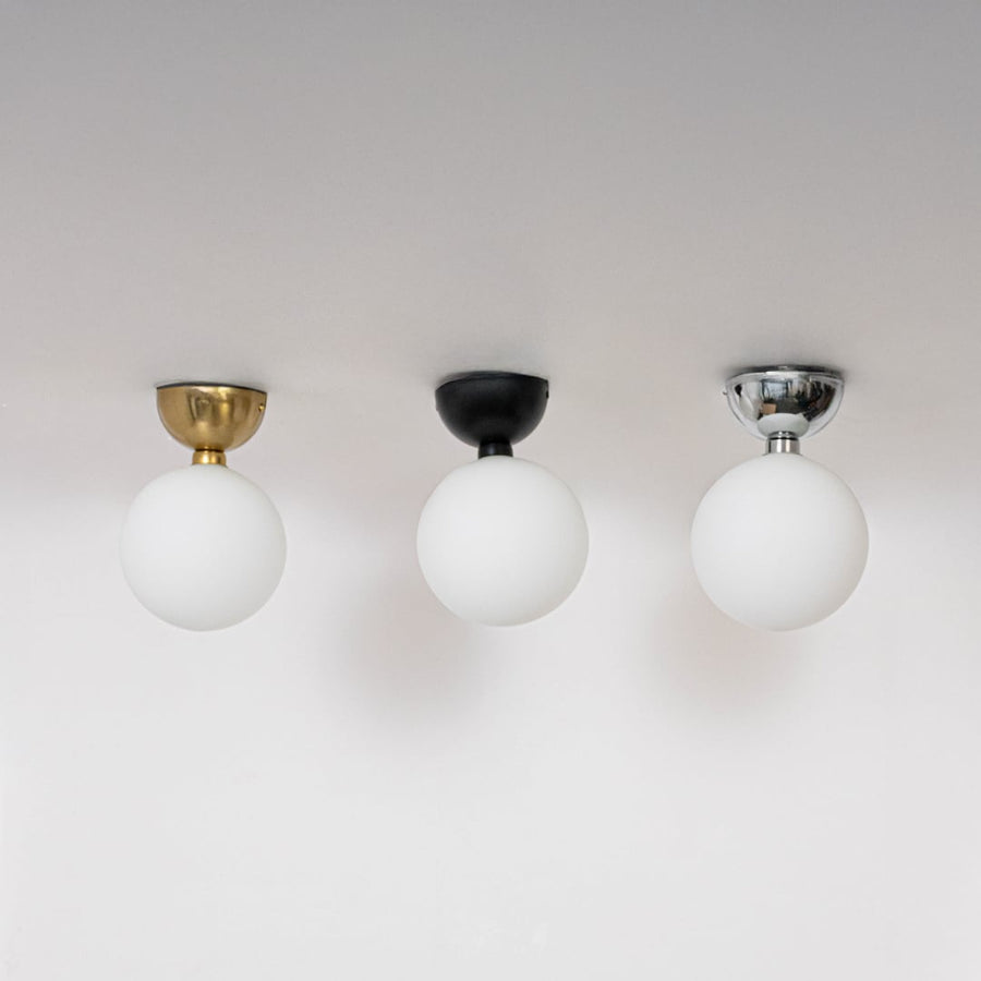 Collection of ceiling lights in chrome gold and black finish with frosted glass globes shown switched off on background.