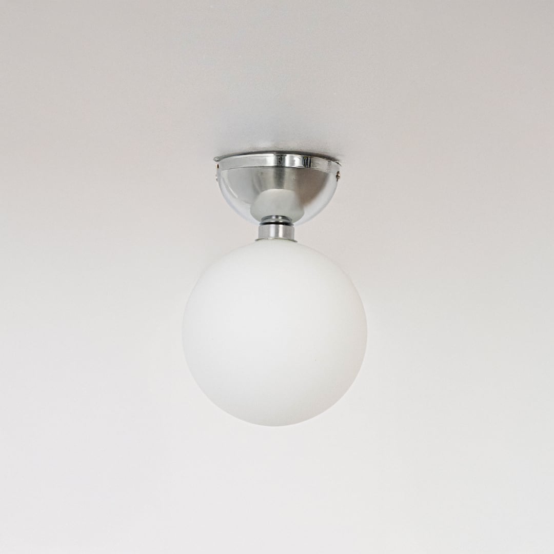 Ceiling light with polished chrome base and frosted glass globe shade shown off on plain white background.