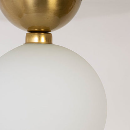 Closeup of ceiling light with brushed gold base and frosted glass globe shade for modern home lighting decor.