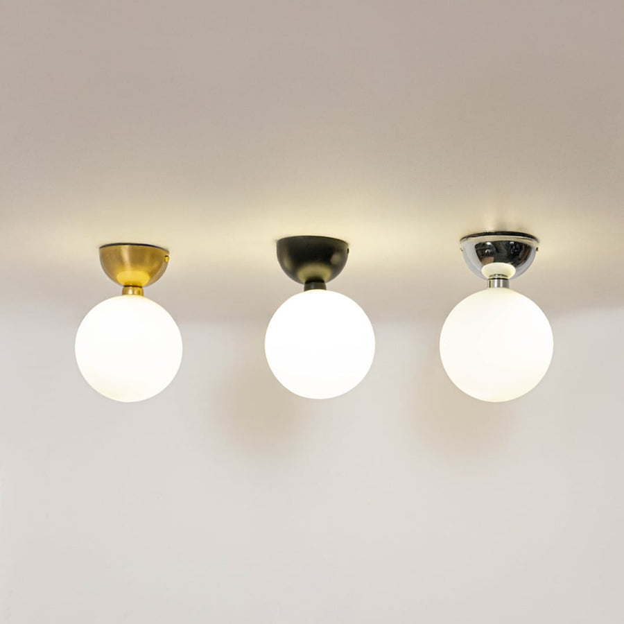 Set of modern ceiling lights in gold black and chrome finish with frosted glass globes glowing on white background.