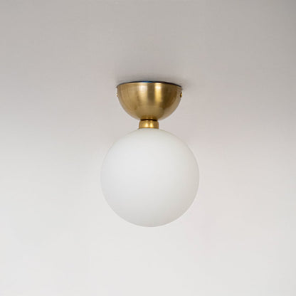 Ceiling light with gold base and frosted glass globe shade shown switched off on plain white background.