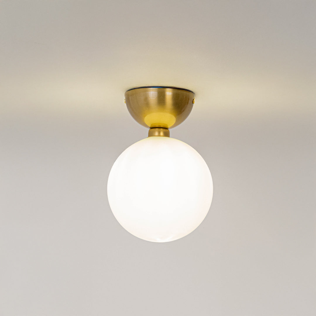 Modern white glass globe ceiling light with gold metal fixture for stylish hallway and luxury decor spaces.