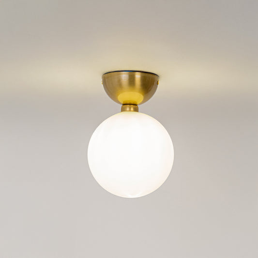 Modern white glass globe ceiling light with gold metal fixture for stylish hallway and luxury decor spaces.