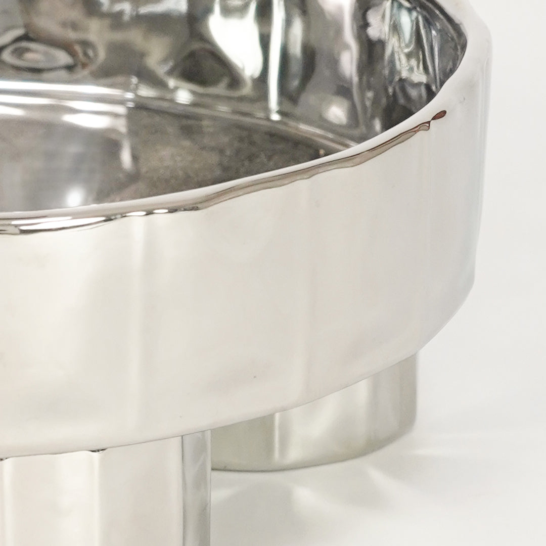Closeup image of silver metal decorative bowl for modern dining table styling with reflective polished finish.