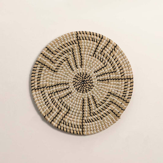 Round handcrafted black and natural seagrass wall basket with geometric stepped zigzag pattern on white background image.