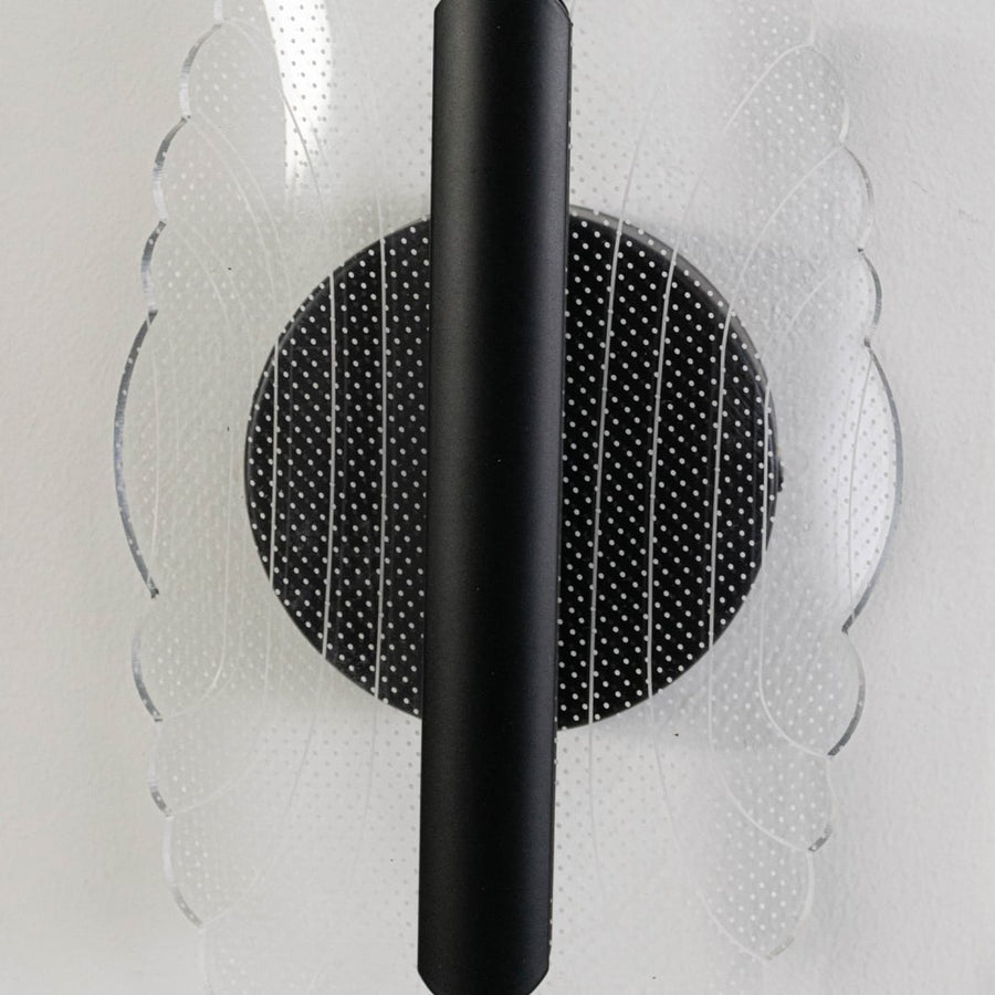 Closeup of black metal wall light with clear acrylic patterned shade highlighting elegant texture and modern finish.
