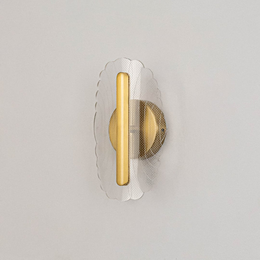 Gold metal wall light with clear acrylic patterned shade shown on a white background with lights off.