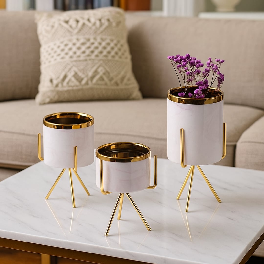 A white marble finish planter with a gold metal stand placed on a soft surface creating a clean lifestyle look for modern home styling.