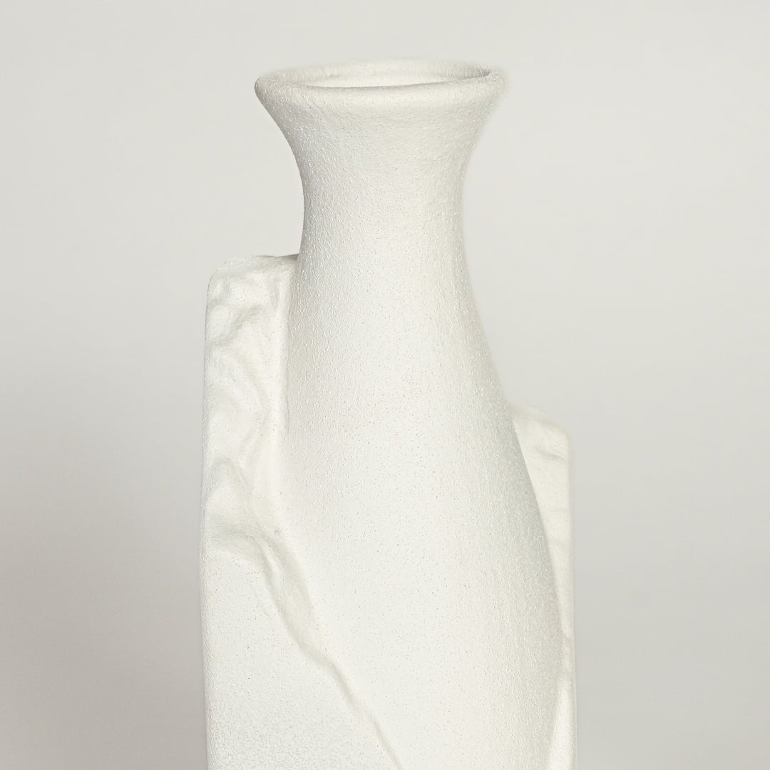 Close up view of white ceramic vase highlighting sculpted crack detail matte texture and minimalist geometric shape.