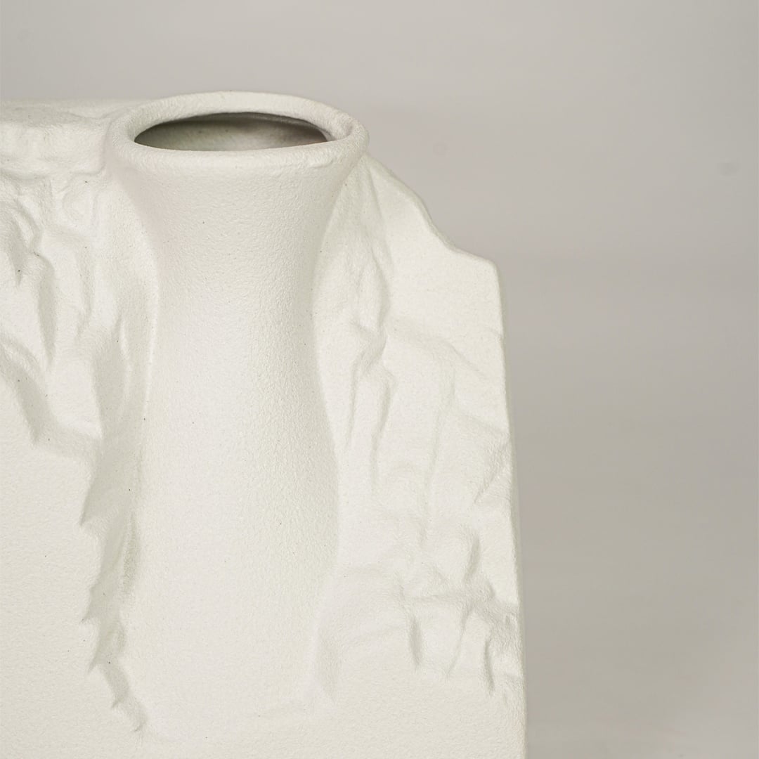 Closeup of white ceramic vase with sculpted textured finish for elegant tabletop and shelf decor styling.
