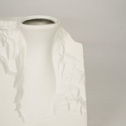 Closeup of white ceramic vase with sculpted textured finish for elegant tabletop and shelf decor styling.