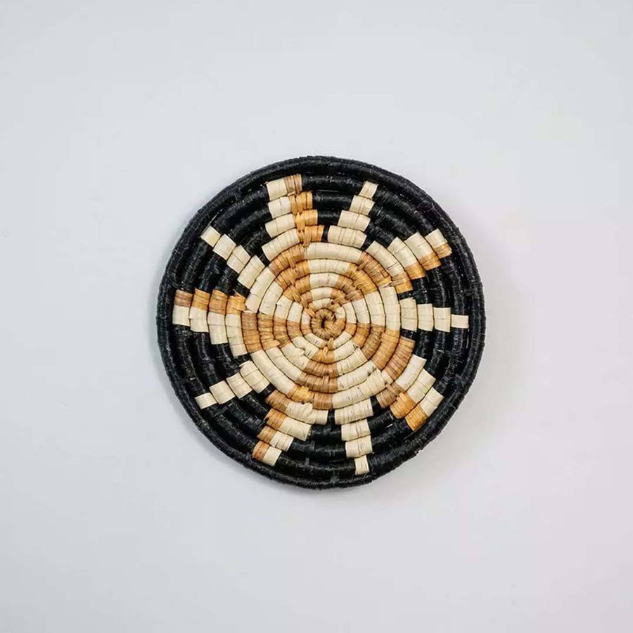 Handwoven seagrass round wall basket decor in natural beige and black with floral star woven pattern on white background.