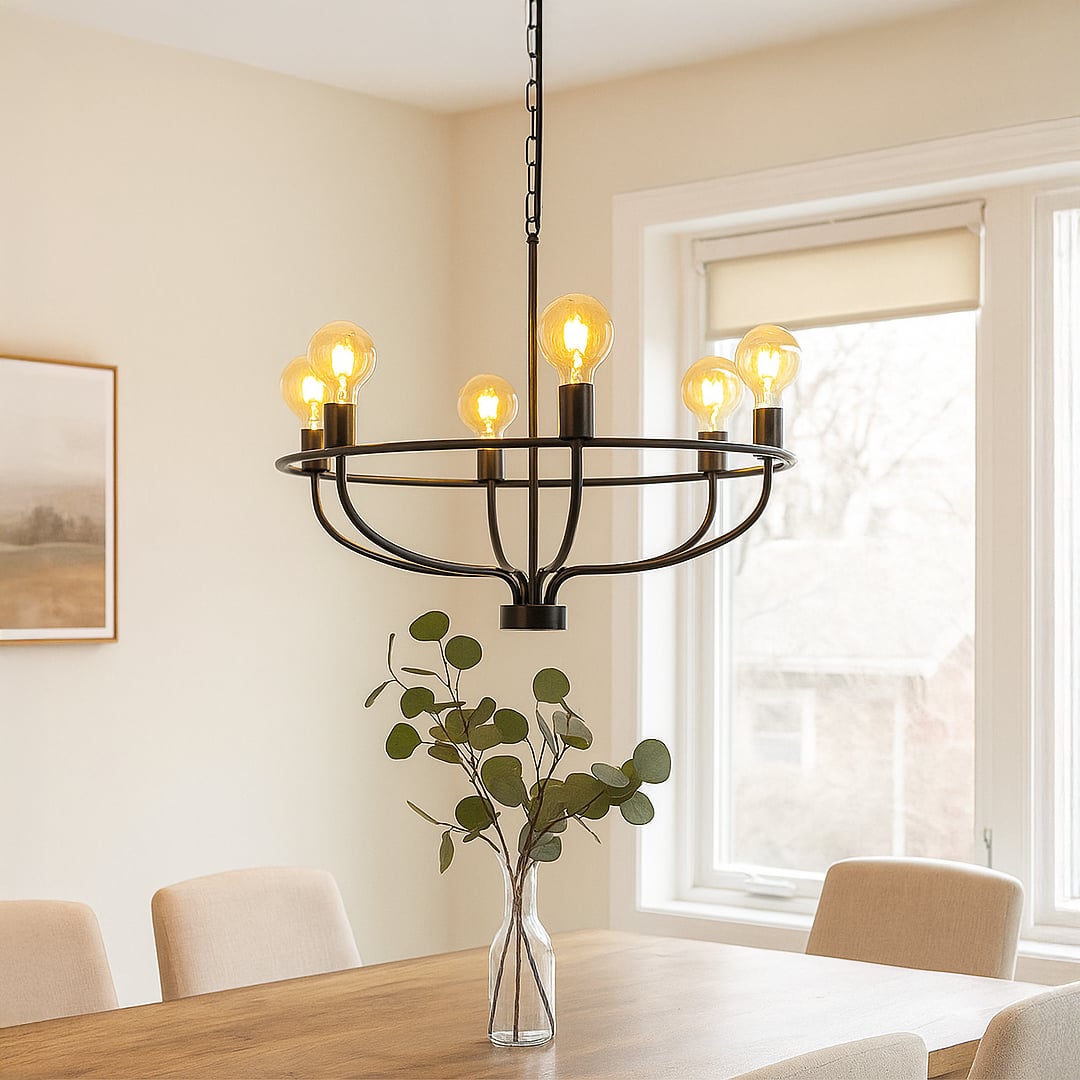 Modern black metal wagon wheel chandelier with amber Edison globe bulbs hanging in interior space creating rustic lighting.