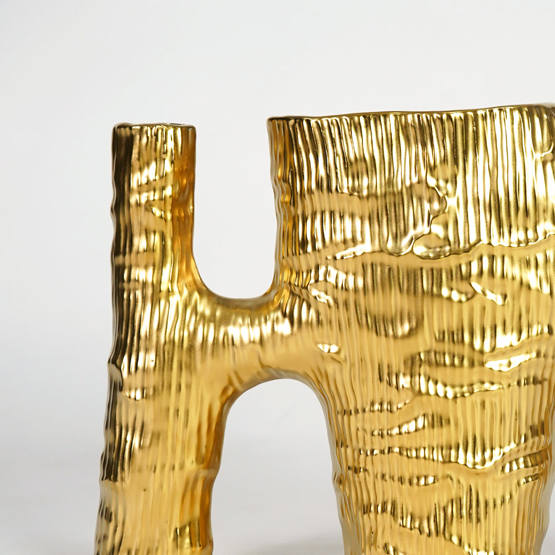 Closeup image of gold metal abstract vase for luxury console table decor with hammered texture styling display.