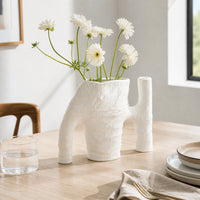 White textured ceramic flower vase with fresh blooms placed on dining table for elegant modern home decor.