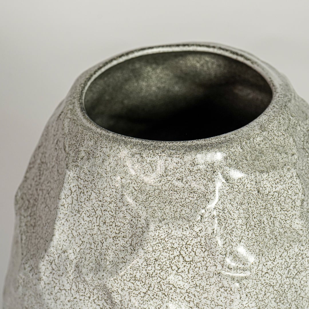 Close up view white textured ceramic vase showing organic sculpted surface glossy finish decorative ceramic accent for home styling.