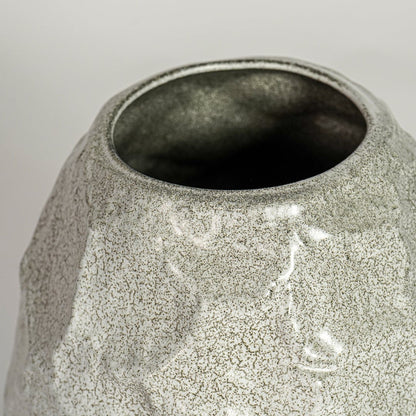 Close up view white textured ceramic vase showing organic sculpted surface glossy finish decorative ceramic accent for home styling.