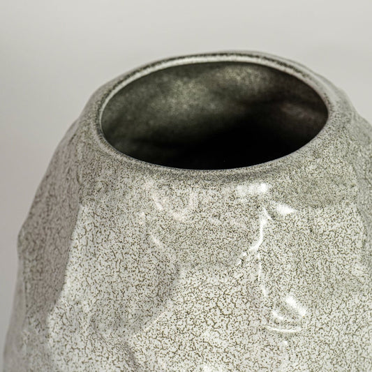 Close up view white textured ceramic vase showing organic sculpted surface glossy finish decorative ceramic accent for home styling.