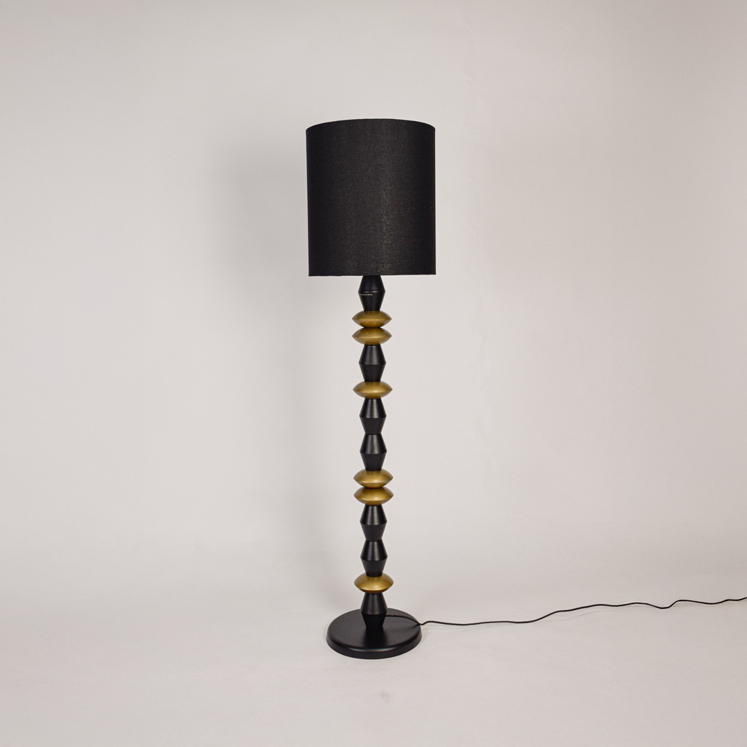 Floor lamp floor light off on white background featuring black fabric shade with geometric black and gold metal base for minimalist product display.