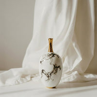 White ceramic decorative vase with grey marble pattern styled on fabric for elegant contemporary home decor settings.