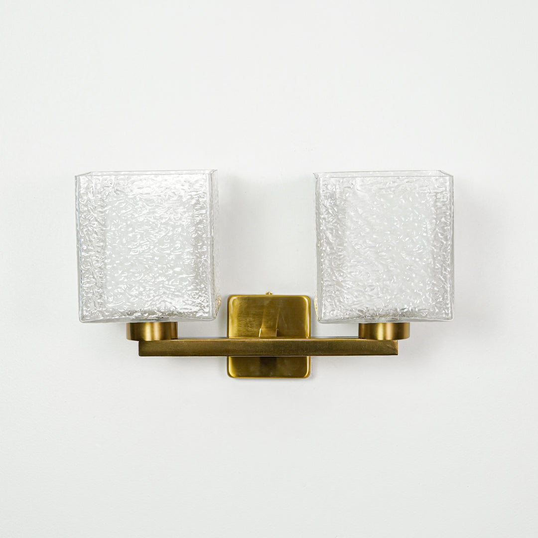 Contemporary gold wall light with ribbed glass shades mounted on clean white wall background ideal for modern interior lighting setup.

