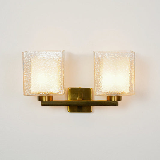 Elegant gold wall sconce with double textured glass shades on neutral wall background perfect for luxury bedroom or living room decor lighting.