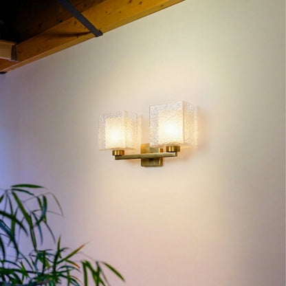 Modern gold wall light with dual frosted glass shades mounted on neutral wall background creating warm ambient lighting for contemporary interiors.