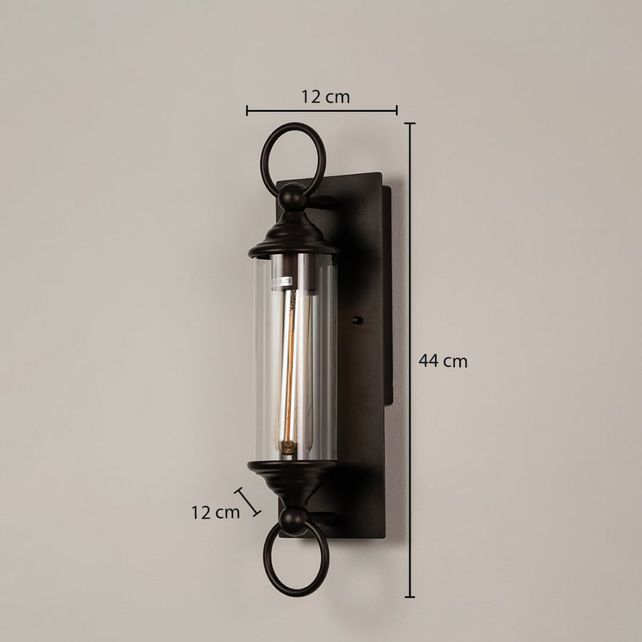 Black metal wall sconce with clear glass tube shown with dimensions 44 cm height 12 cm width and 12 cm depth for easy fitting.