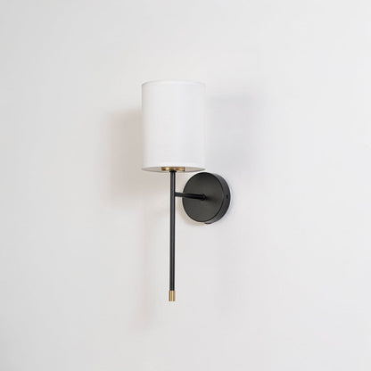 Modern white drum shade wall light fixture with black metal frame and brass accents turned off on clean white background.
