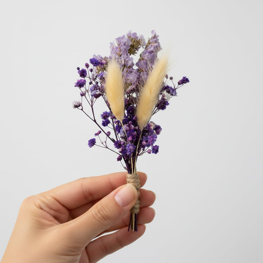 Artificial dried flower stem with beige pampas and purple accents held in hand for minimalist vase Decor styling.