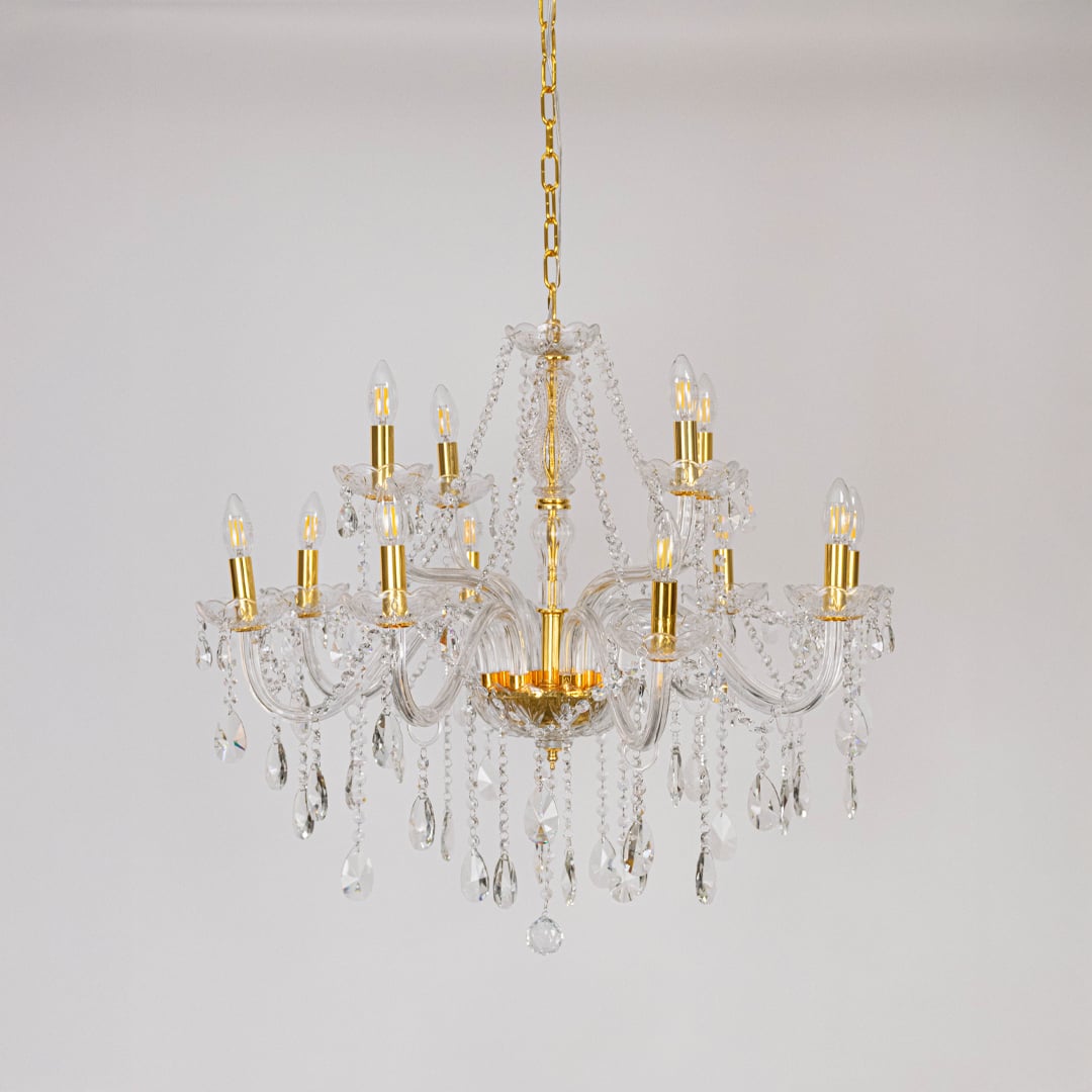Crystal chandelier with gold detailing displayed off on white background highlighting luxury light fixture.