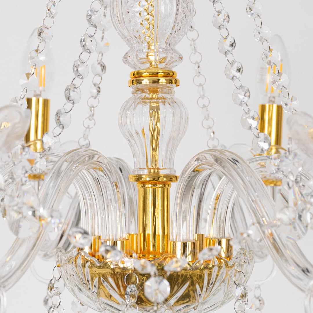 Detailed closeup of gold chandelier with crystal chains and glowing candle lights highlighting elegant design.