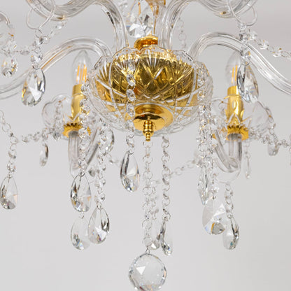 Closeup of gold chandelier showing crystal detailing glass arms and candle style bulbs for luxury ceiling decor.