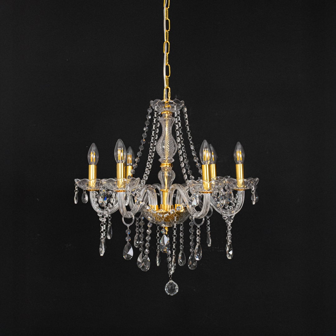 Gold chandelier with lights off highlighting crystal drops and glass body photographed on black background.
