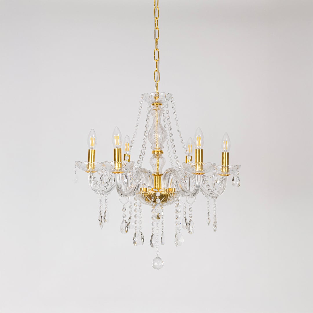 Gold chandelier with lights off featuring crystal accents and glass frame on plain white background.