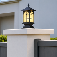 Traditional black iron arched grid glass pillar post lantern light on white concrete gate post for villa driveway entry.