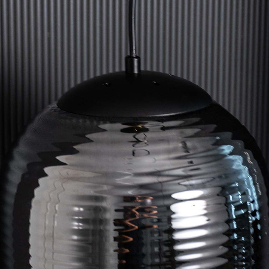 A detailed close view showing the ribbed smoked glass surface with warm light shining through creating a modern elegant glow.