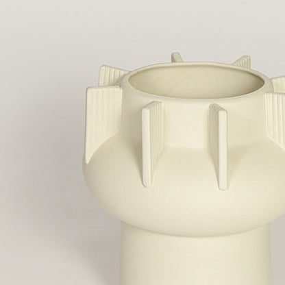 Close view of beige textured ceramic vase with ribbed sculptural details highlighting matte finish for table or shelf placement.