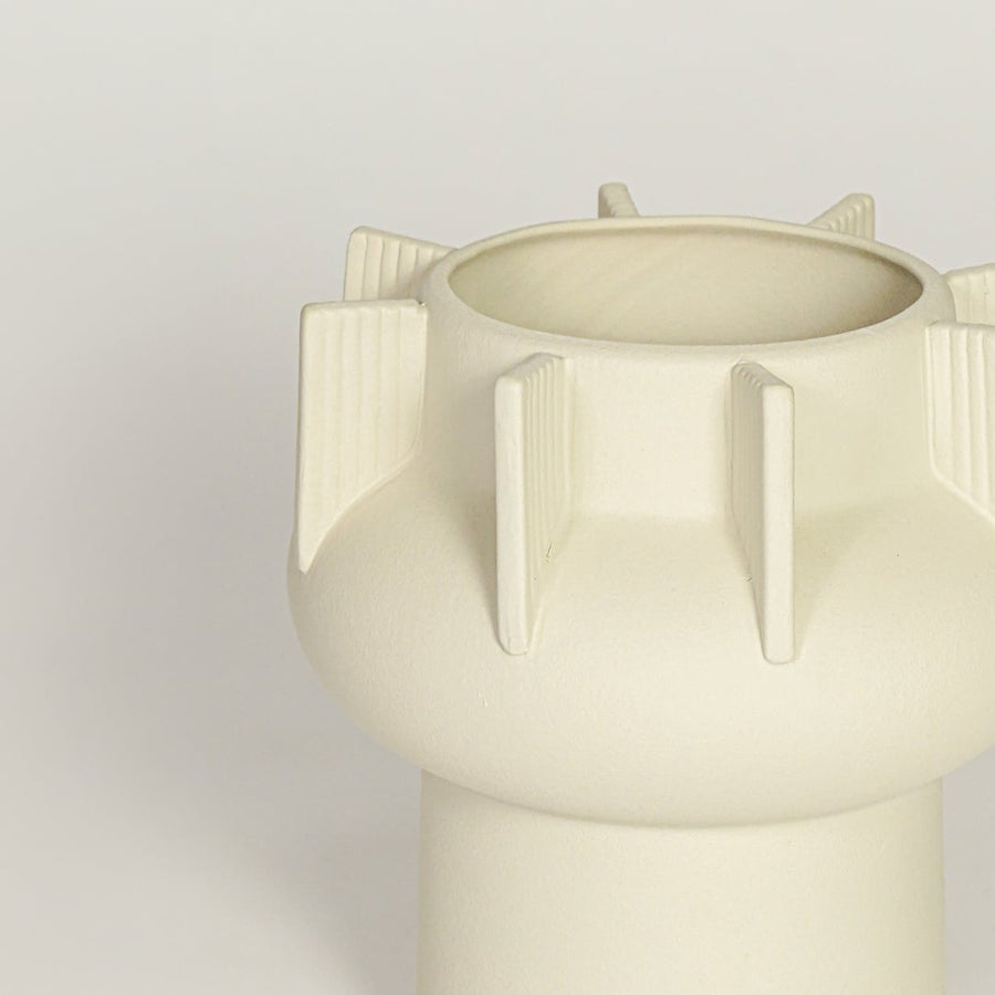 Close view of beige textured ceramic vase with ribbed sculptural details highlighting matte finish for table or shelf placement.