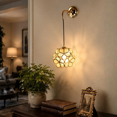 Ornate gold brass geometric cage ball wall sconce light casting warm shadows on living room wall for luxury interior decor.