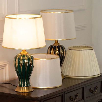Table lamp with green and gold ceramic base and white shade featured in a coordinated scene for elegant interior decor.
