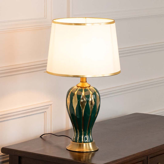 Green ceramic table lamp with fabric shade displayed on a wooden table offering warm classic interior lighting.