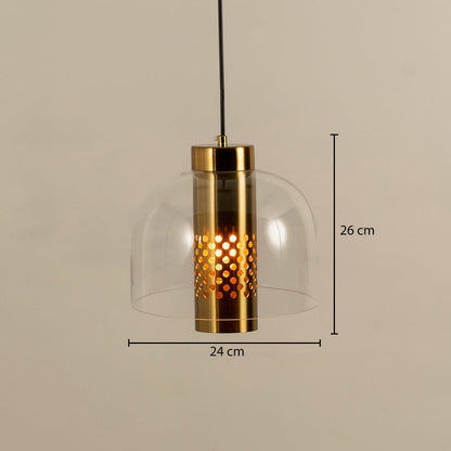 Clear dome pendant light with a perforated gold inner cylinder glowing warmly shown with dimensions of 26 cm height and 24 cm width.