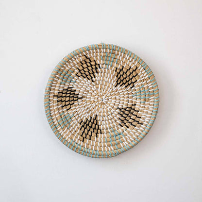 Handwoven seagrass round wall basket decor in natural beige with green leaf pattern displayed on white background.