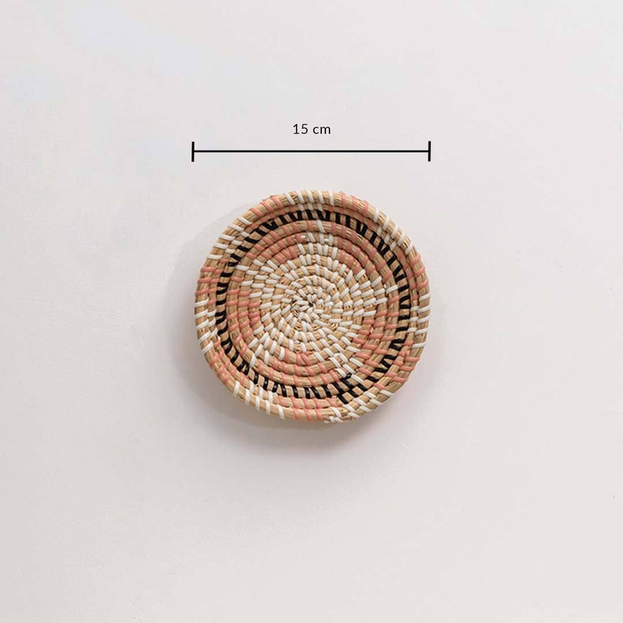 Handwoven seagrass round wall basket decor in natural beige with coral woven center and size guide on white background.