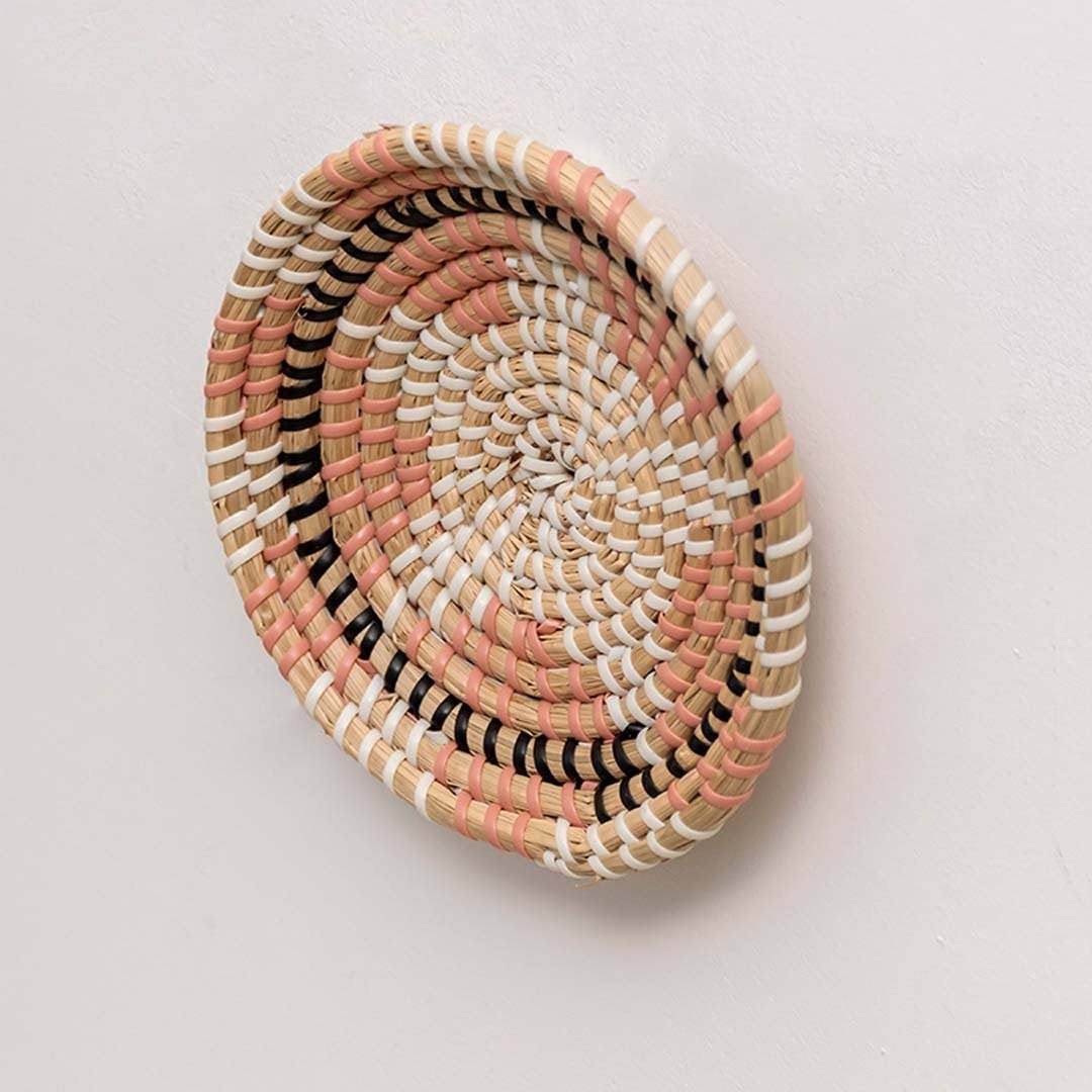 Handwoven seagrass round wall basket decor in natural beige with raised woven profile shown from side angle on white.