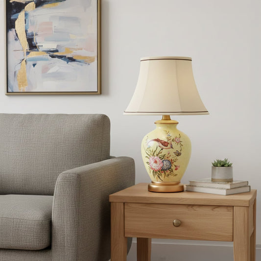 Yellow ceramic table lamp with hand painted floral bird artwork gold metal base and fabric shade styled on classic console.