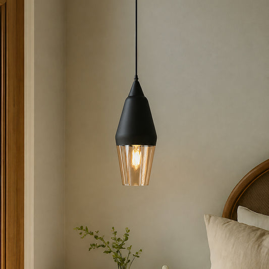 A modern black pendant light with a clear ribbed glass shade hanging in a warm, neutral-toned bedroom setting.