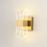 Gold wall light with ribbed clear glass shade illuminated on a clean white background for clear bright visibility.