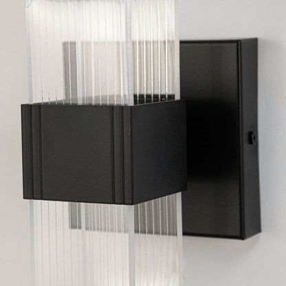 Closeup of black wall light with ribbed clear glass shade highlighting smooth texture and elegant curved design.
